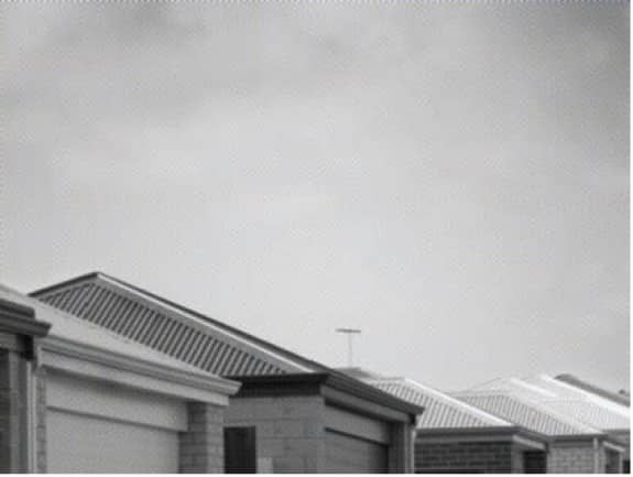 New suburban rooftops dream under a clouded sky.