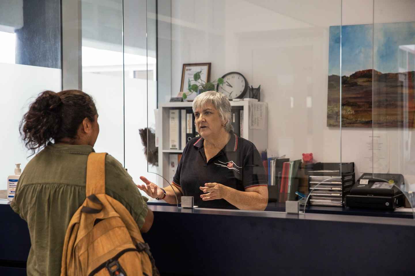 A Salvos worker welcomes a young woman into her office.